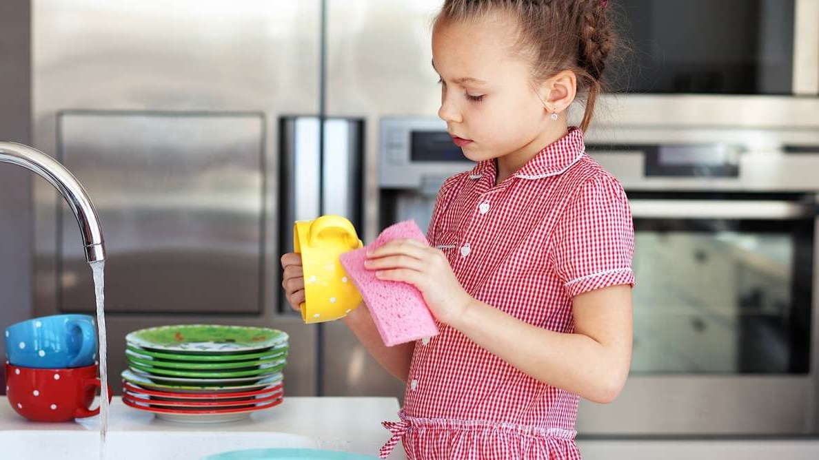 Девочка 5 лет моет посуду в раковине
