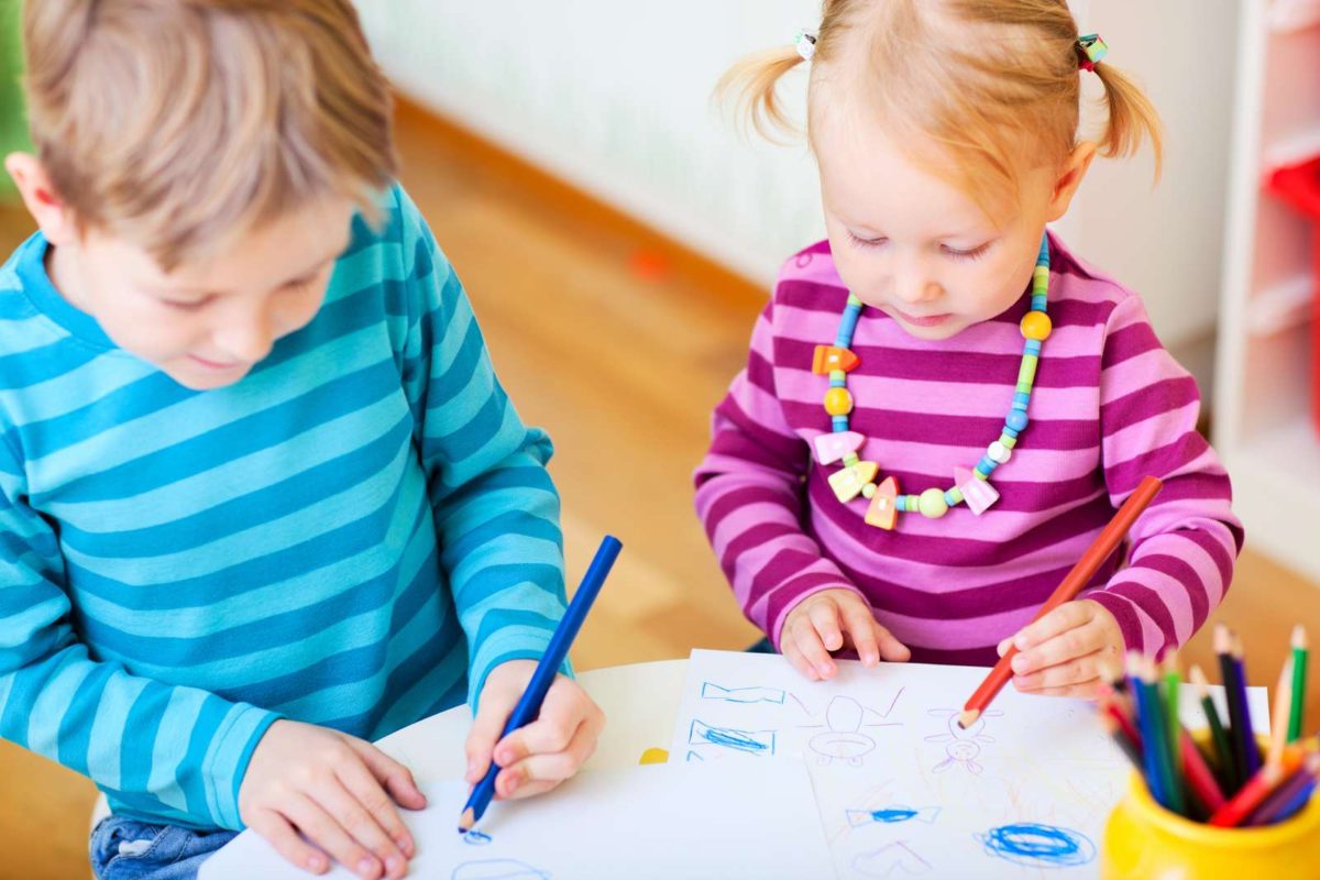 Мальчик с сестрой левши рисуют карандашами на листах бумаги