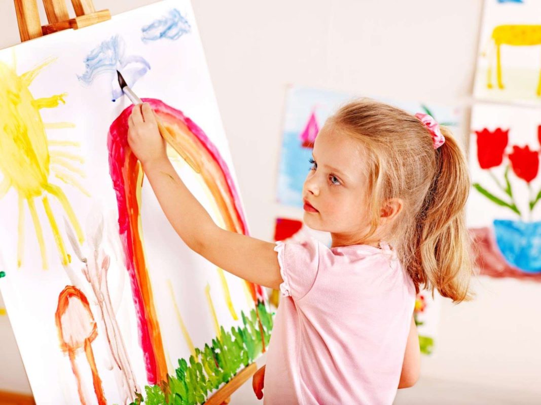 Девочка рисует левой рукой на мольберте