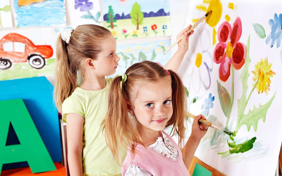 Две девочки-левши рисуют на мольберте