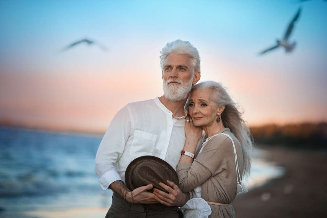 Пожилая пара стоит на берегу моря