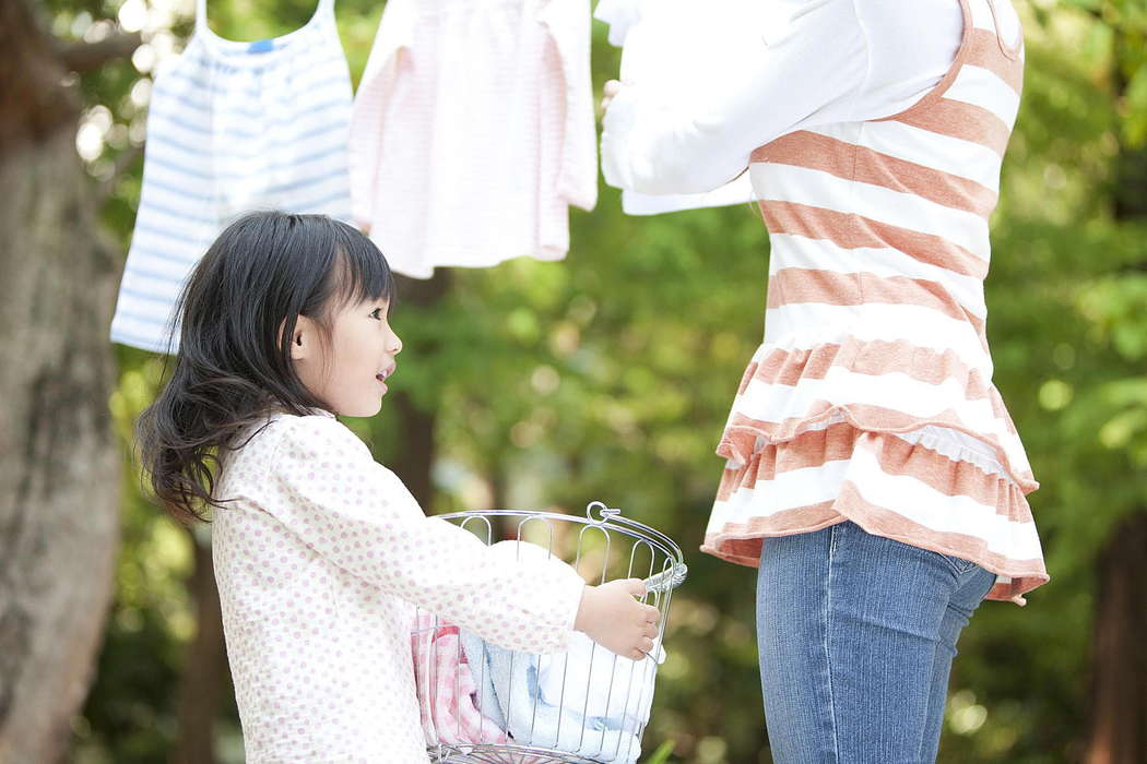 Девочка помогает маме собирать постиранное белье