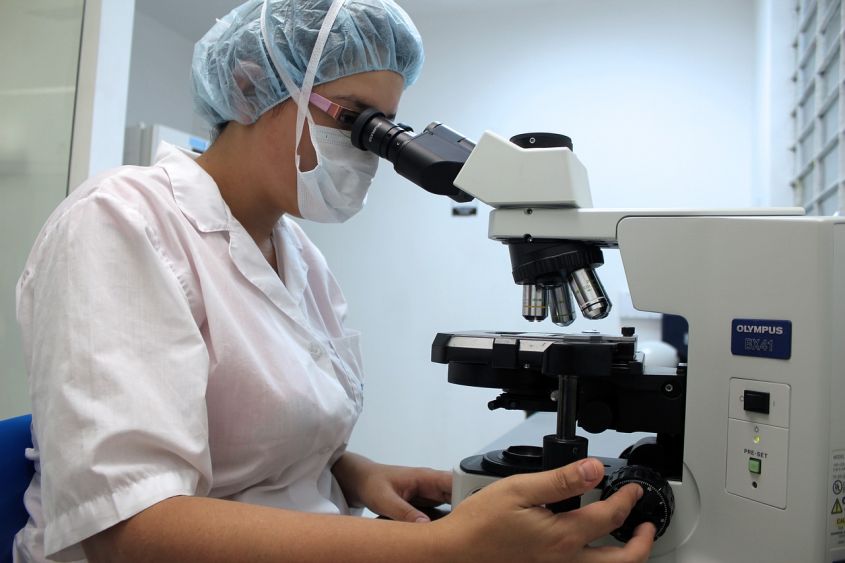 Женщина лаборант смотрит в микроскоп