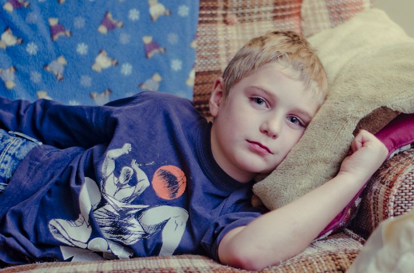 Мальчик в синей футболке лежит на диване