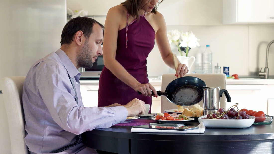 Женщина готовит еду и накладывает мужу в тарелку