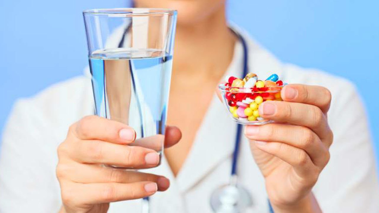 Медсестра со стаканом воды и таблетками в руках
