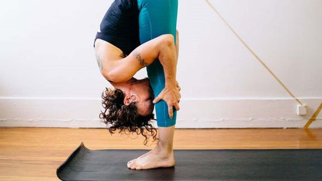 Женщина выполняет сгиб вперед поза йоги