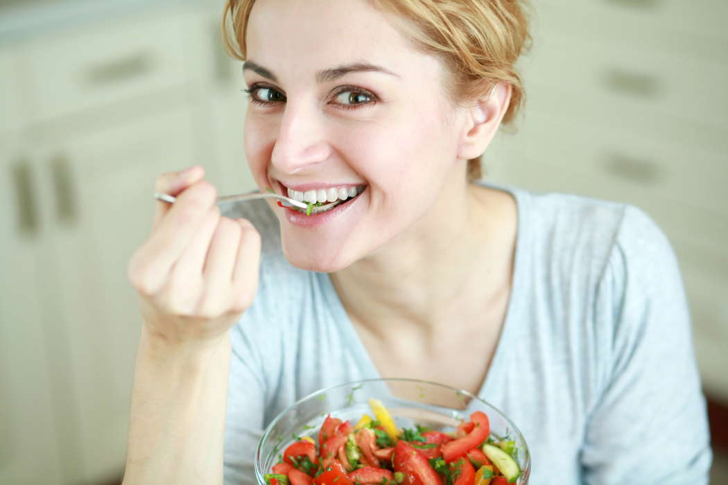девушка на диете ест салат из помидоров