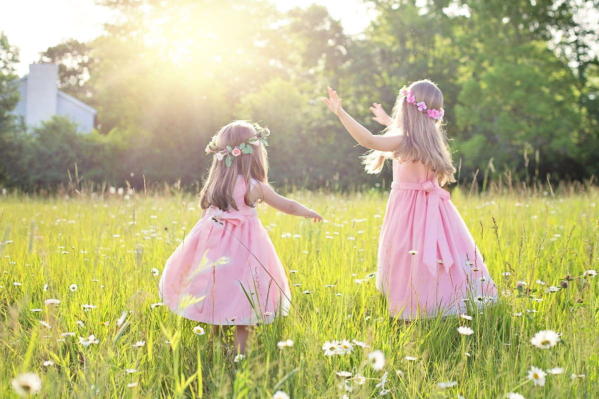 две девочки в розовых платьях летом на траве в поле
