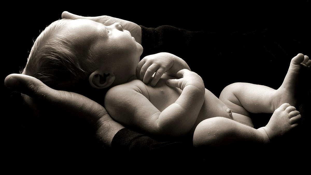 новорожденный спит на руках черный фон