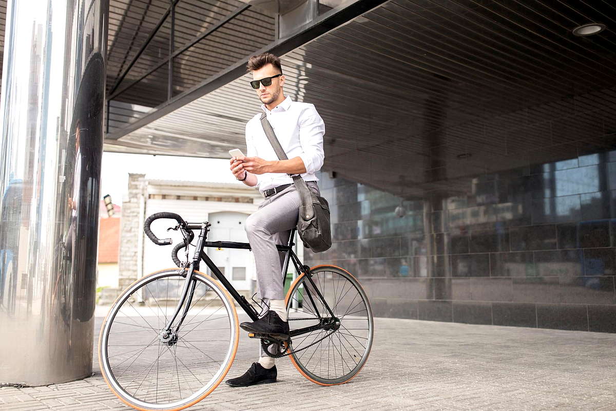 Человек на велосипеде читает сообщения на телефоне