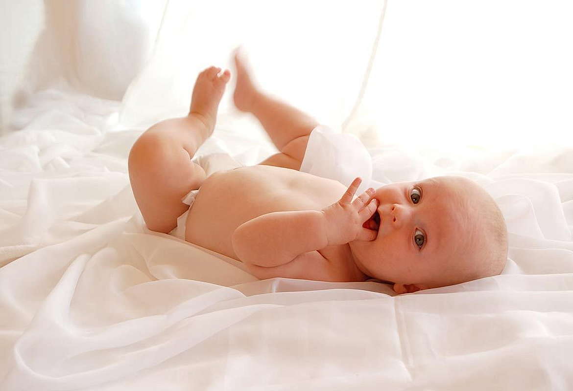 Новорожденный ребенок на белой простыне